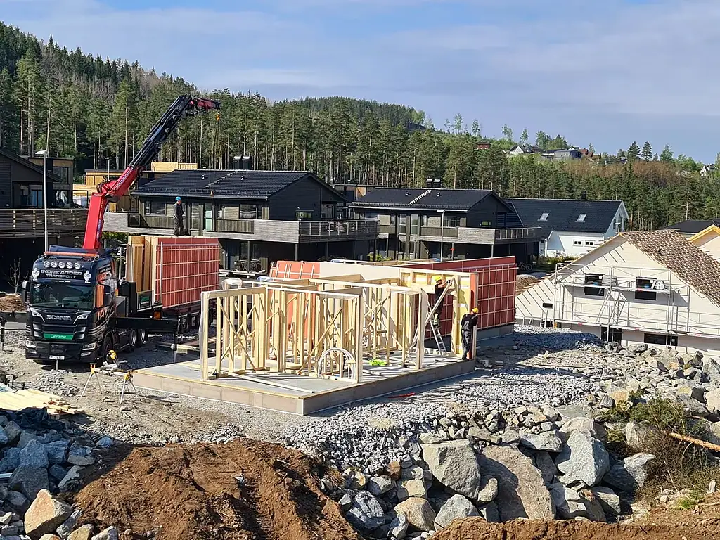 Modulpluss Sør byggeplass med trestammer og kran, nye boliger under oppføring, byggearbeid, hytte bygging, trelast, trekonstruksjon, husbygging, norsk boligmarked, tre- og byggindustrien.